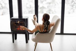 Woman with burning sparkler near fireplace in the house in winter