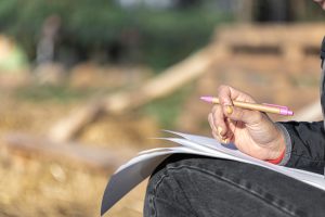 A woman's hand holds a pen and sheets of paper, copy space.